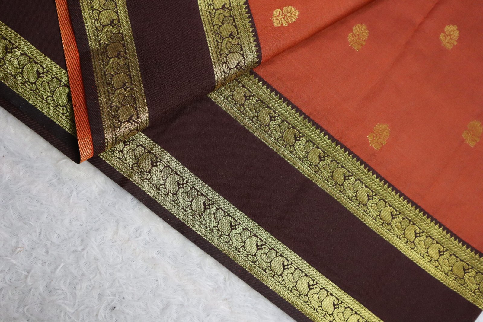 Intricate woven zari borders featuring traditional peacock and mango designs on a premium soft silk saree